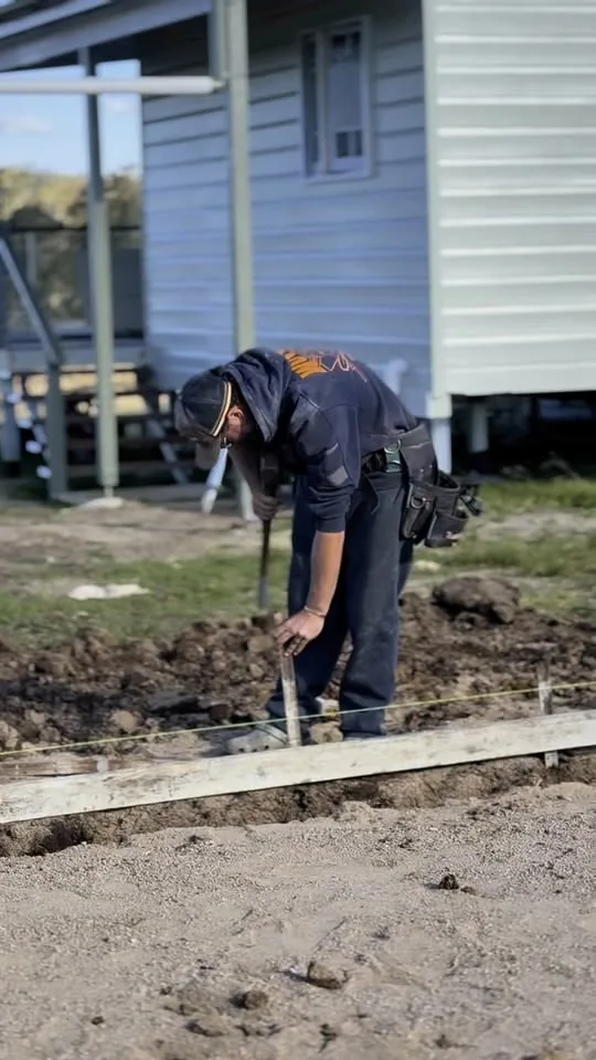Worker finishing a concrete edge beside a house